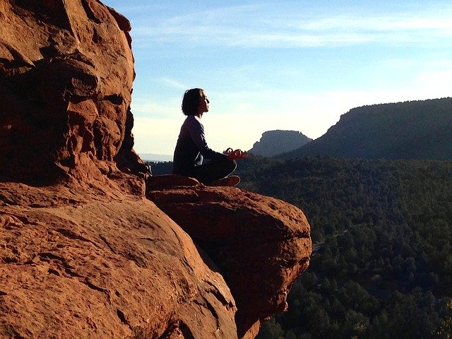 Žena sedí v tureckom sede na skale a medituje.jpg